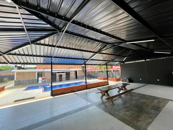 Zona social techada con mesas junto a la piscina